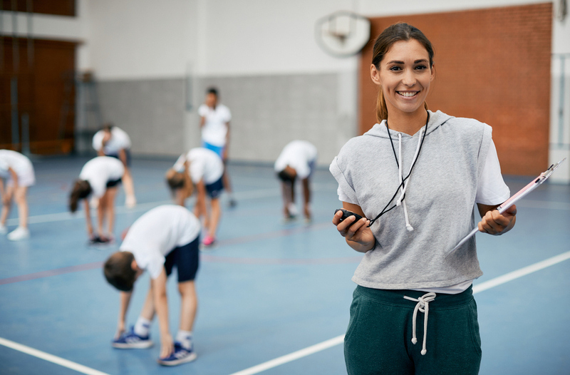 Young,Happy,Coach,Using,Stopwatch,During,Pe,Class,At,School